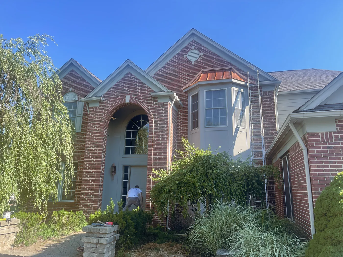 An arched brick entry with a copper bay roof and gray stucco.