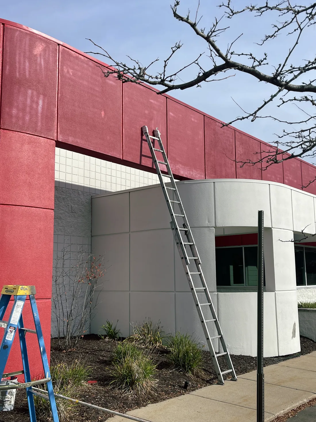 A red commercial facade with a ladder set against it.
