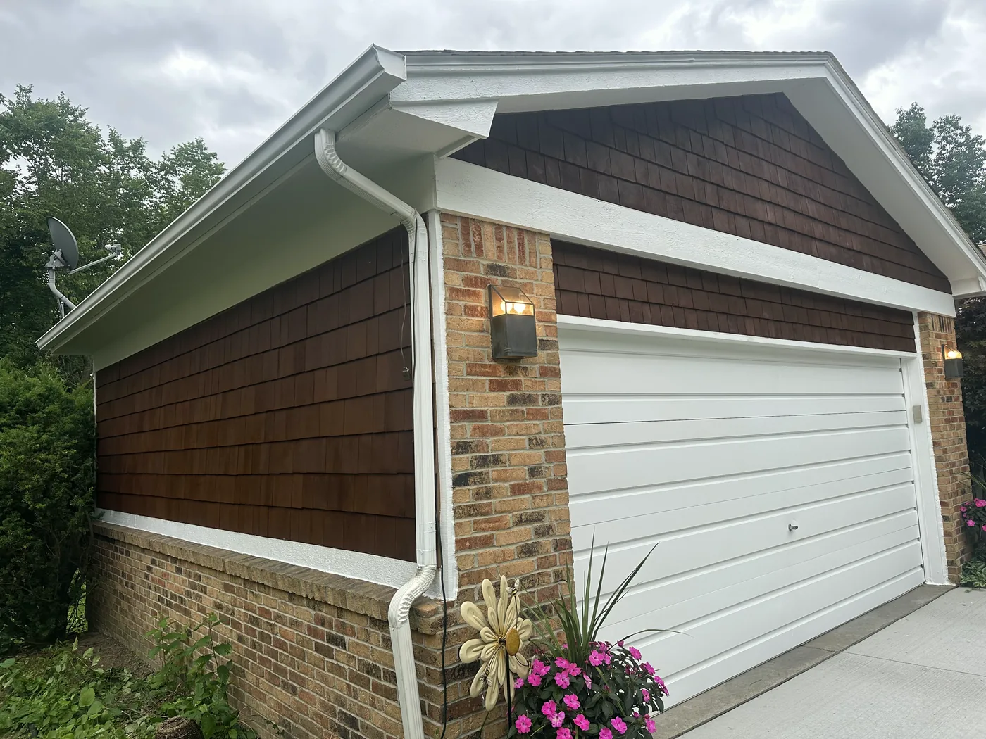 A garage gable of stained cedar shakes with white trim and a white door.